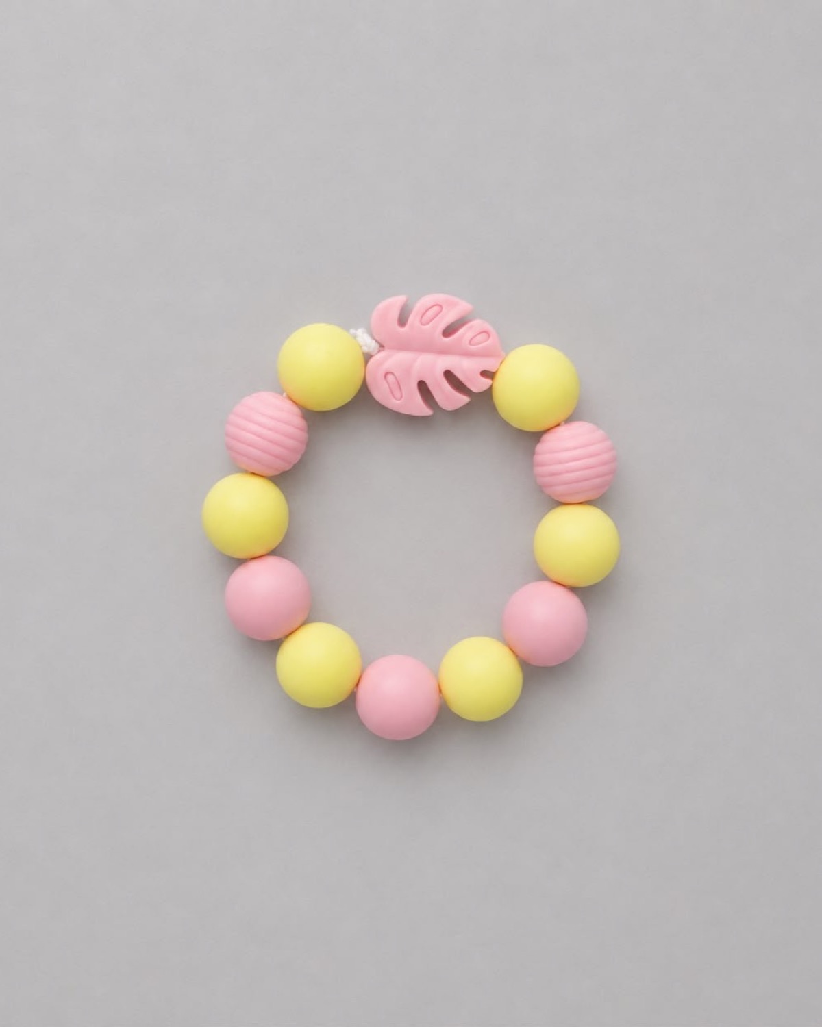 Anneau de dentition Feuille Douce : perles jaune poussin et rose bonbon, deux perles striées roses et une feuille monstera